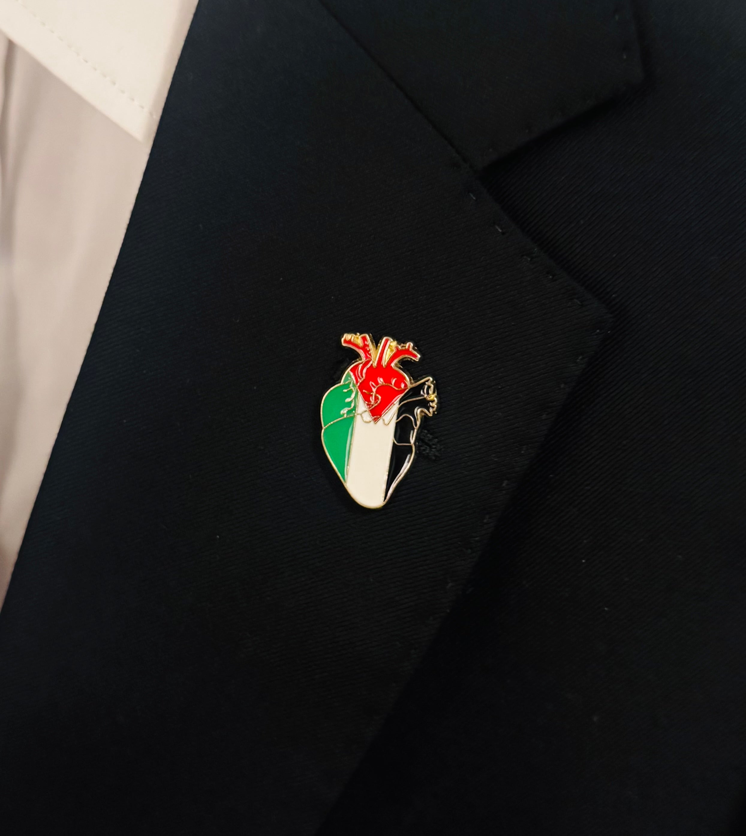 Pin formet som et hjerte med Palestina-motiv festet på svart jakke