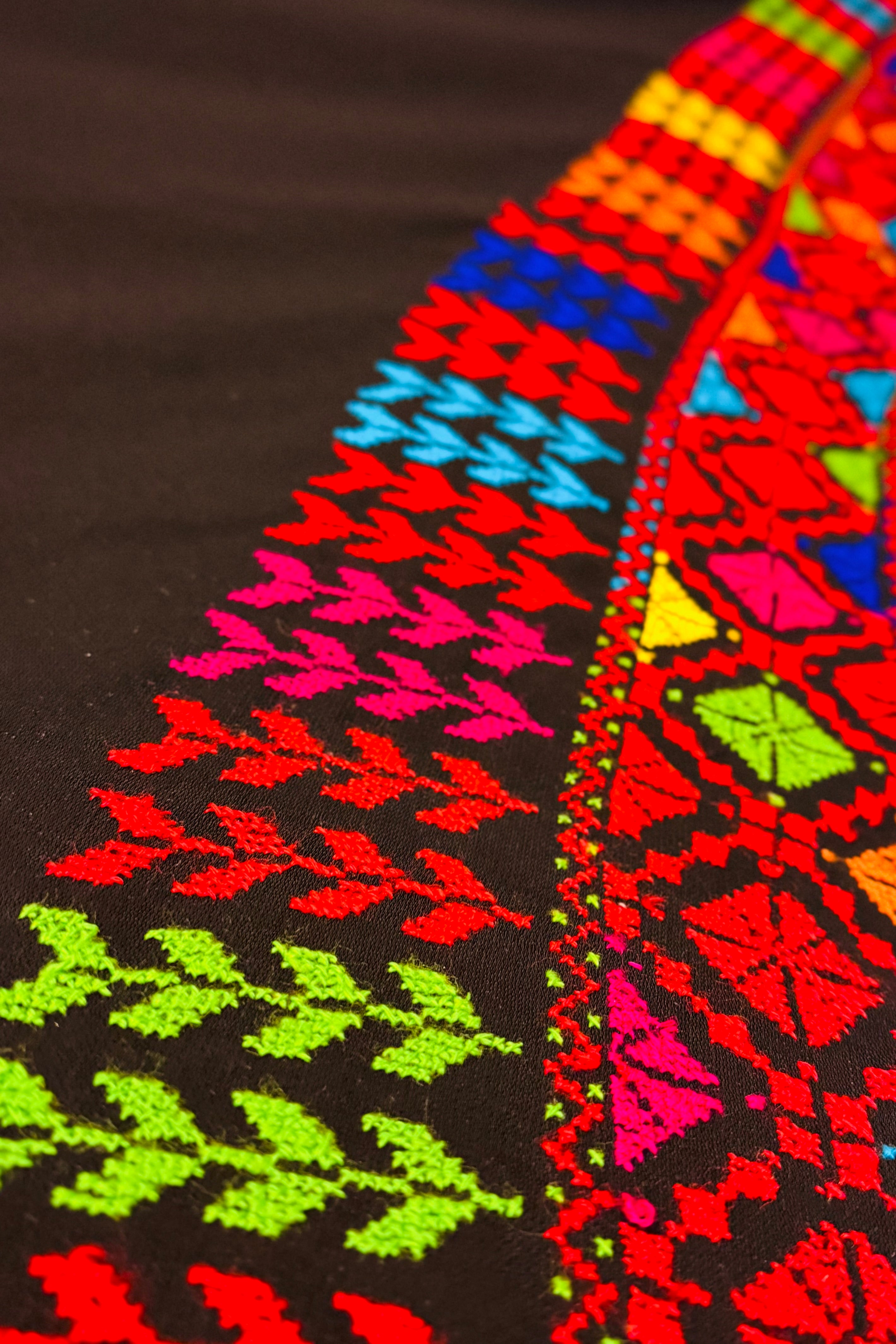 Skrått nærbilde av fargerikt palestinsk tatreez-broderi som fremhever kontraster, sting og tradisjonelle geometriske detaljer
