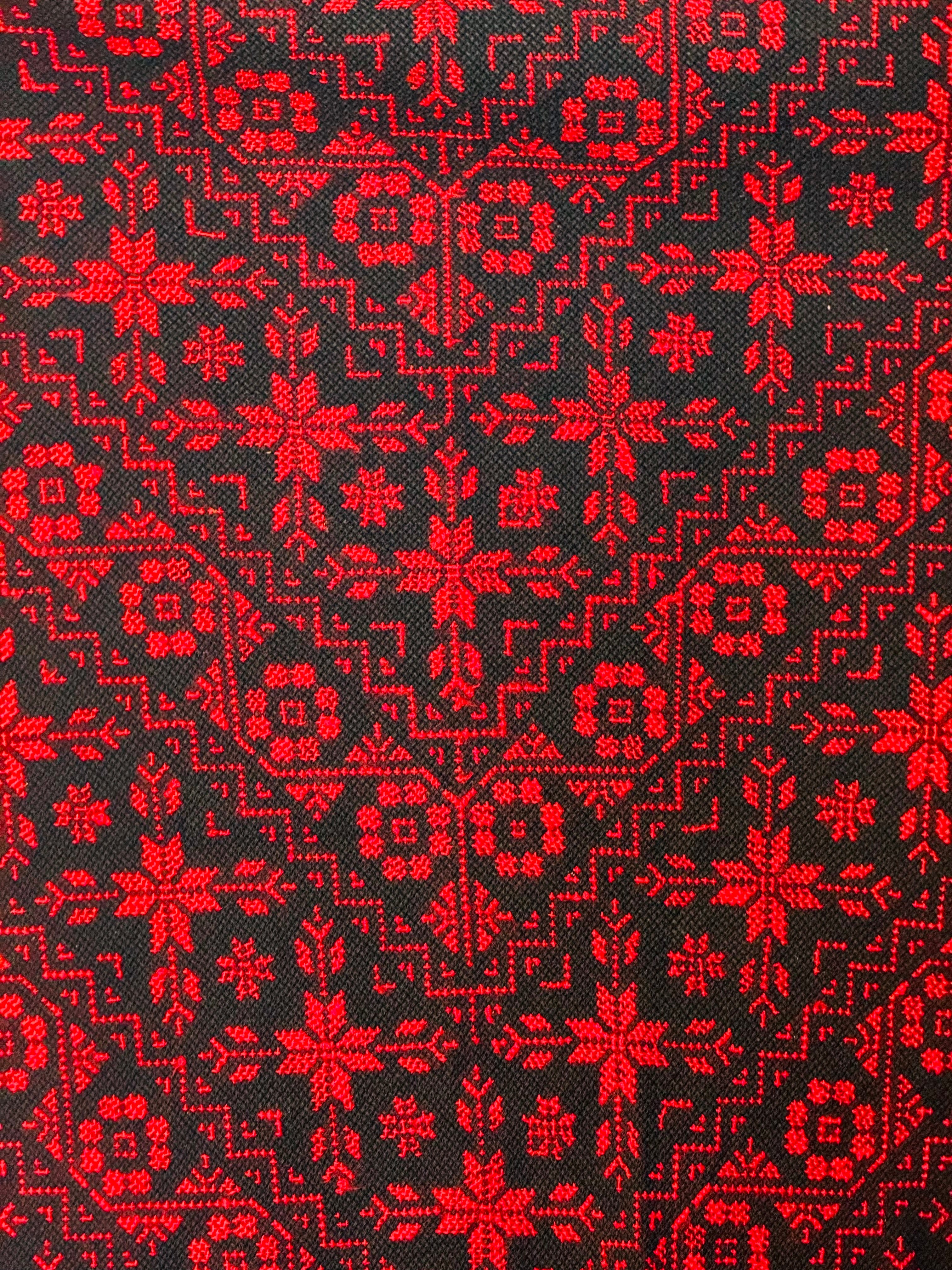 Detaljert nærbilde av tatreez-mønster i røde og svarte farger, tradisjonelt palestinsk broderihåndverk