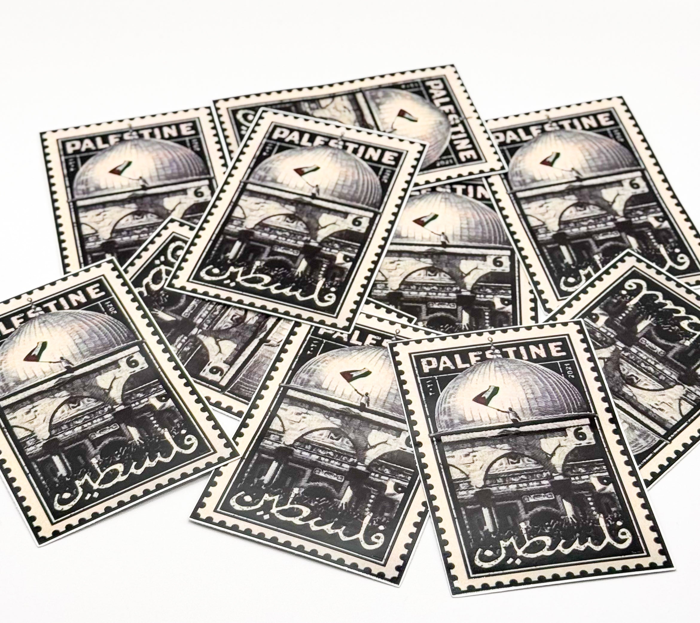 Flere klistremerker med frimerke-design og Palestina-motiv lagt utover en lys flate.
