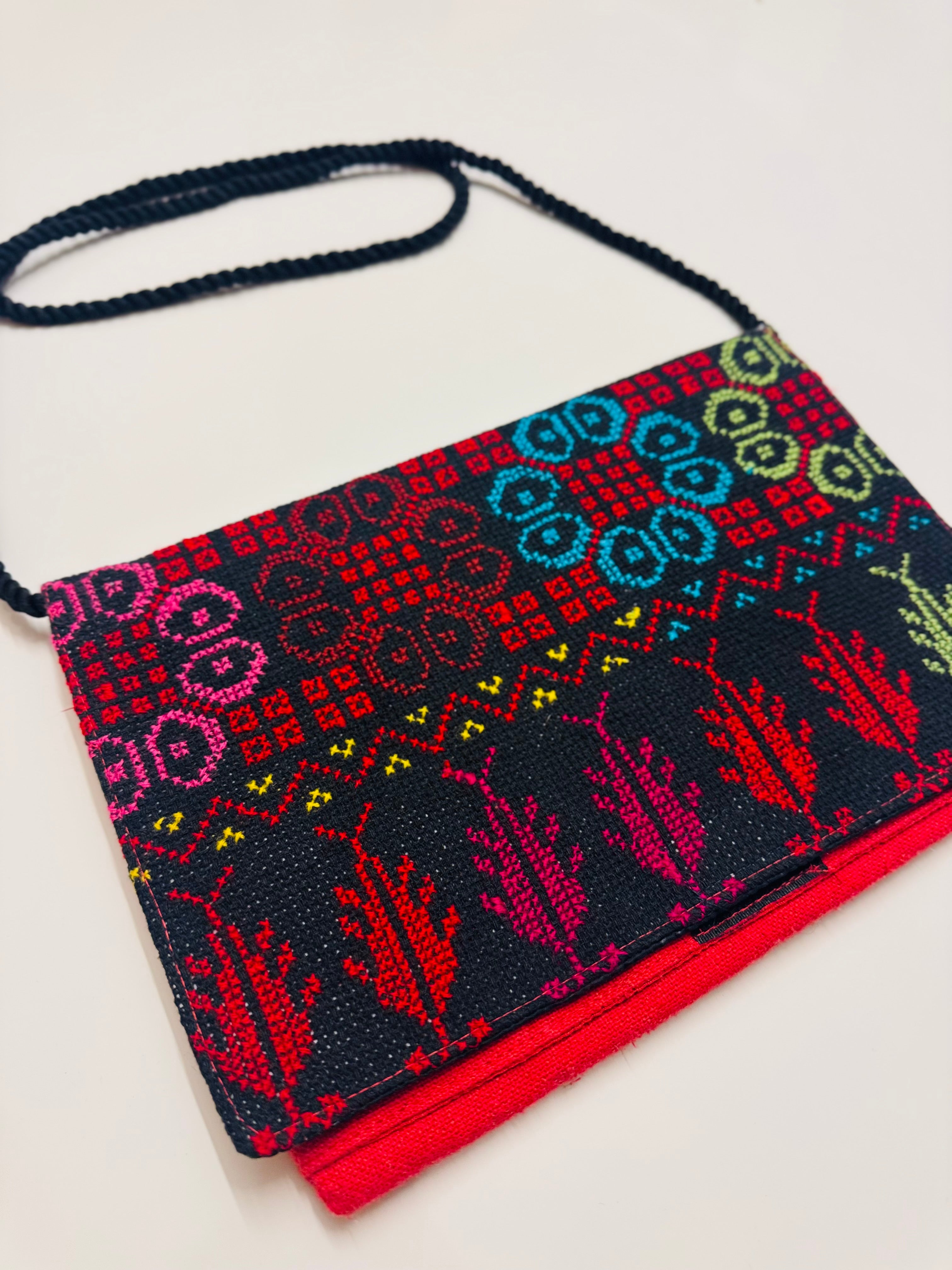Fargerik tatreez-veske fotografert fra skrå vinkel, med brodert mønster som gir dybde i designet.