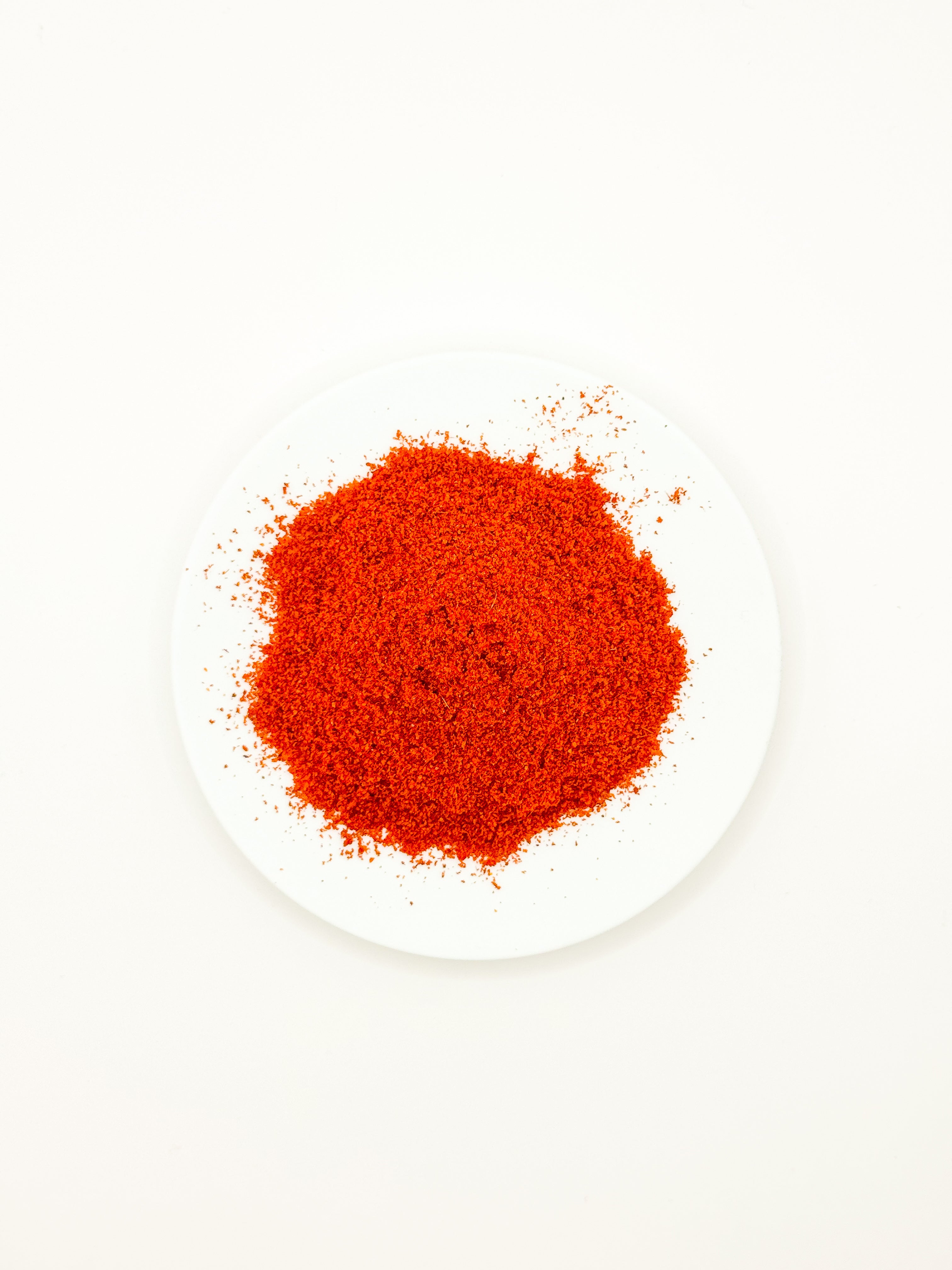 Rød palestinsk kyllingkrydderblanding servert på hvit tallerken mot ren hvit bakgrunn, finmalt krydder med intens farge og enkel presentasjon