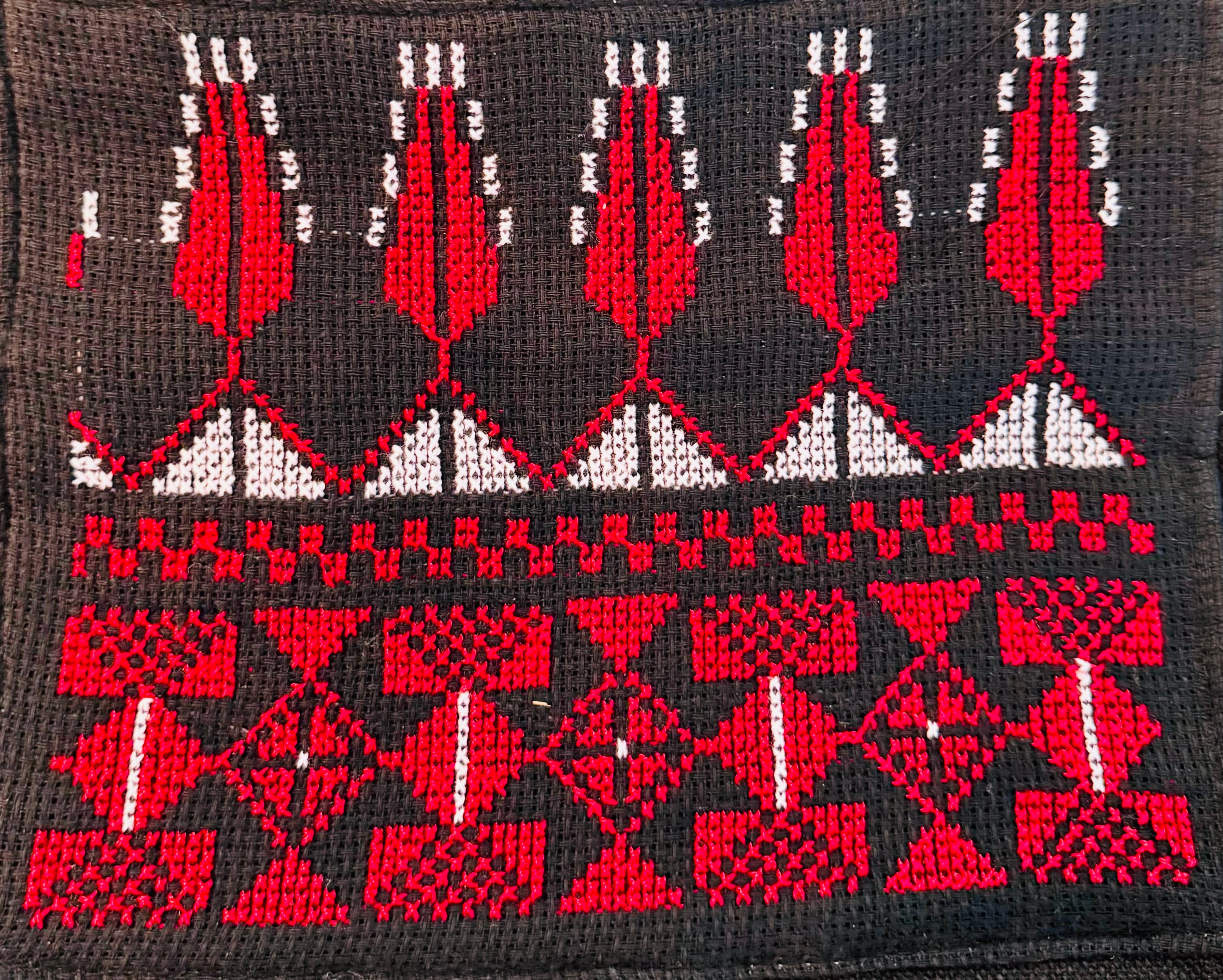 Makrobilde av tatreez-broderi på tøystoff fra en tote bag, med fokus på geometrisk struktur og presis utførelse.