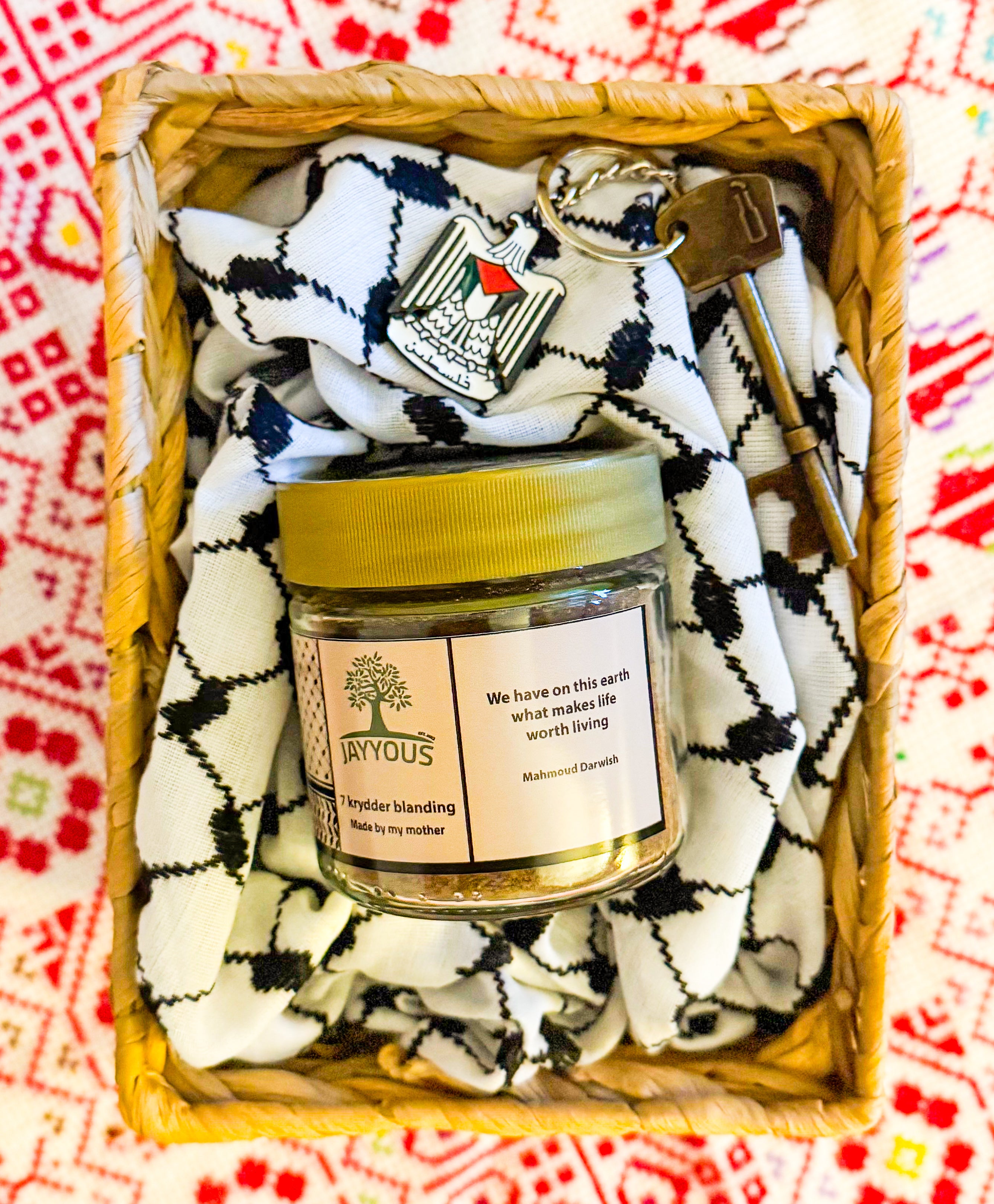 Gavekurv med 7 krydderblanding fra Jayyous, palestinsk nøkkelring og keffiyeh-tekstil, presentert i flettet kurv på tradisjonelt mønstret underlag