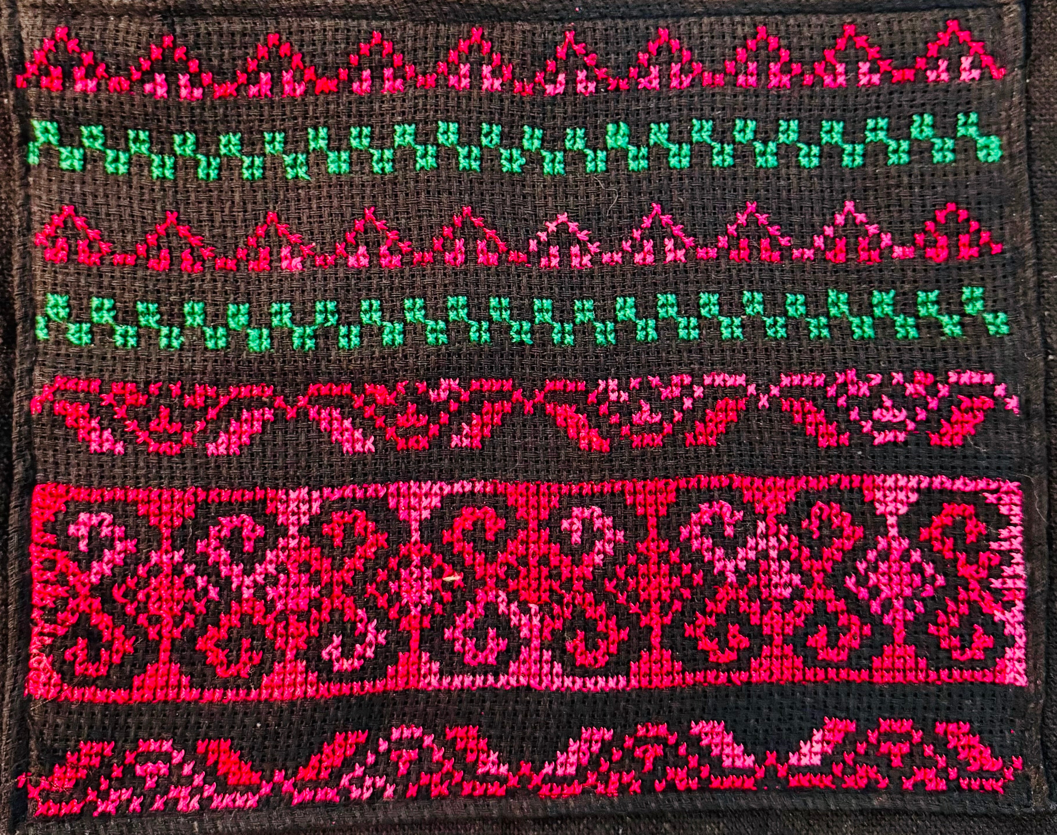Tatreez-mønster sett tett på tote bag-materiale, som viser tekstur i stoffet og dybde i broderte former.