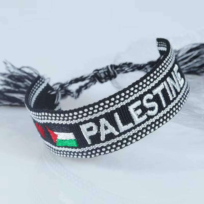 Brodert armbånd fotografert fra skrå vinkel, med teksten «Palestine» integrert i mønsteret.