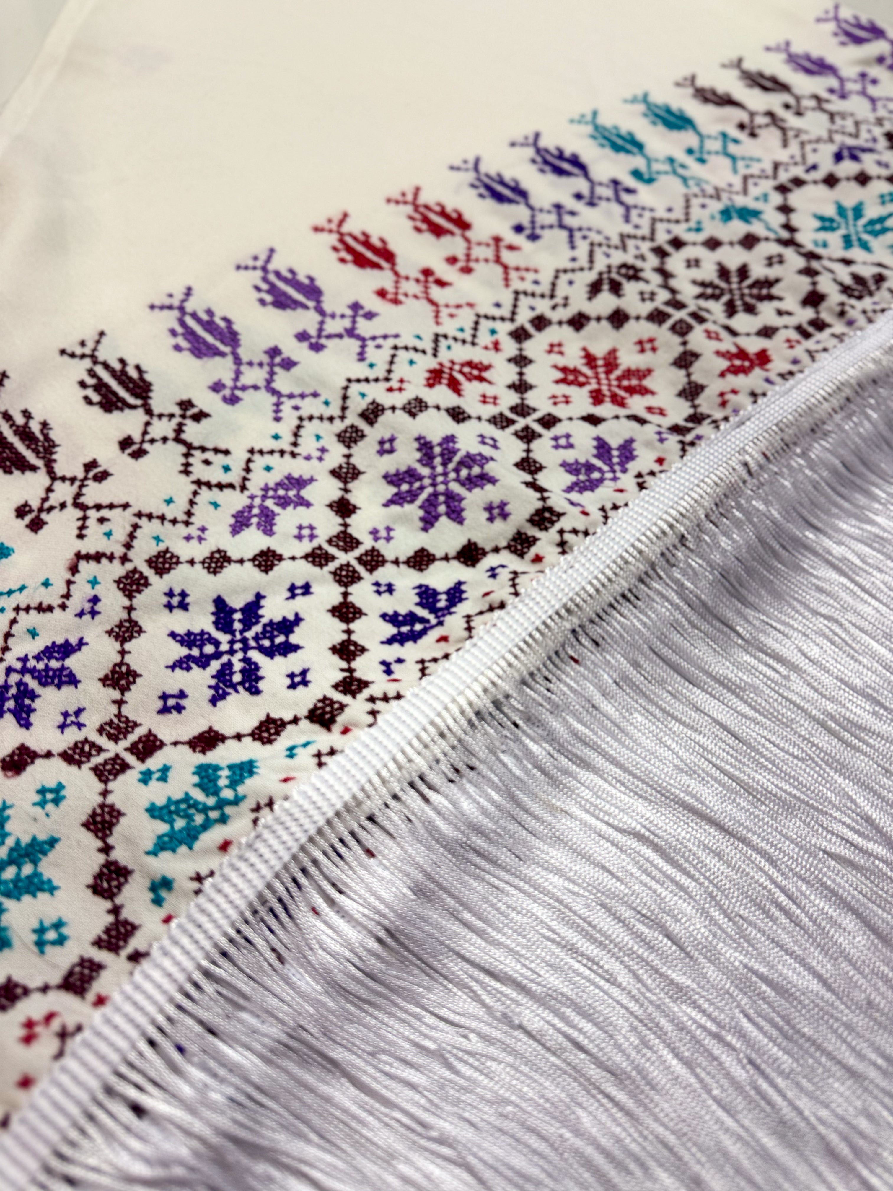 Detaljert vinkelbilde av hvitt tatreez-sjal med synlige palestinske geometriske broderier