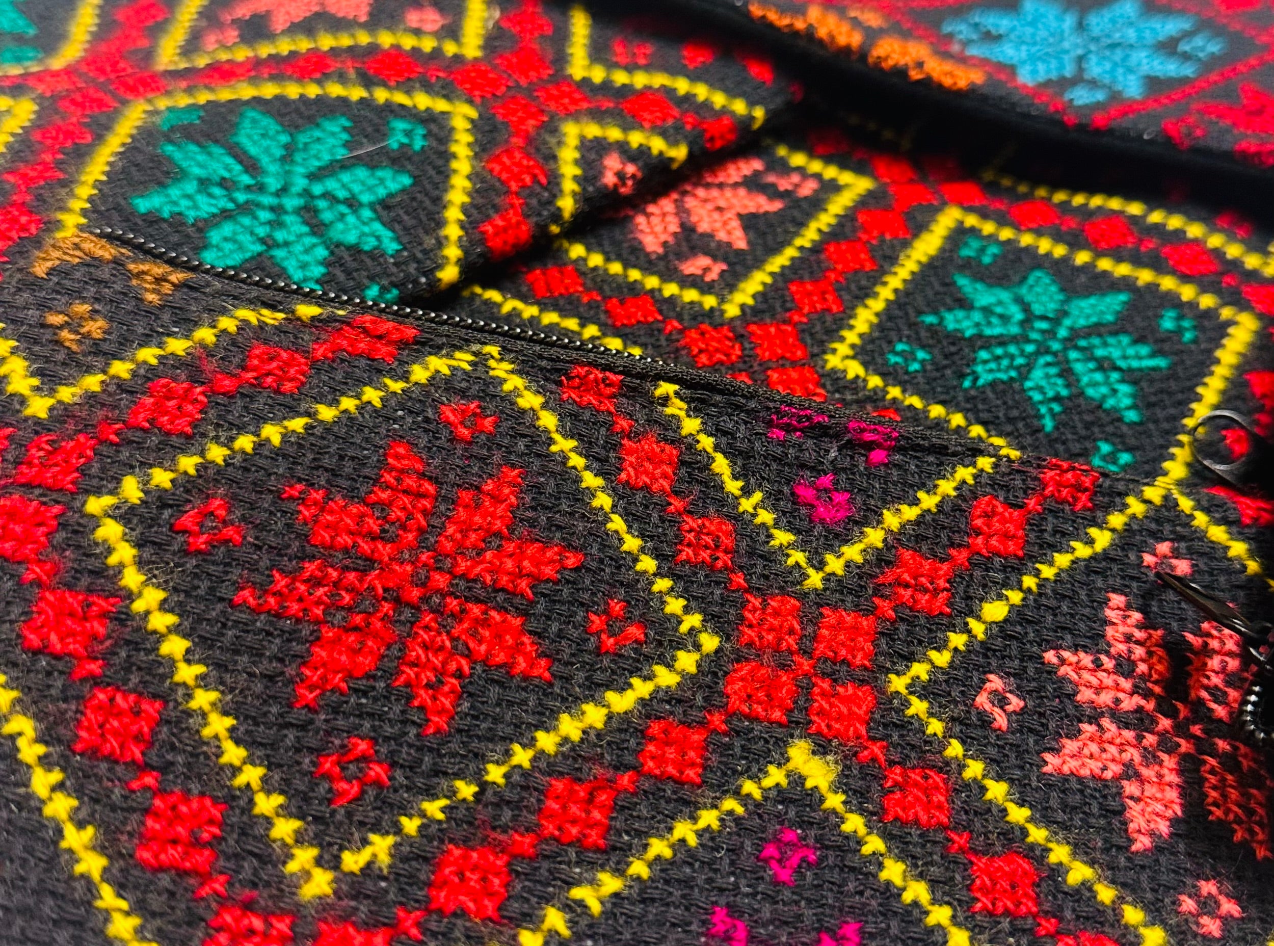 Nærbilde av fargerikt tatreez-broderi på lommebok, med tydelige kontraster i mønsteret.