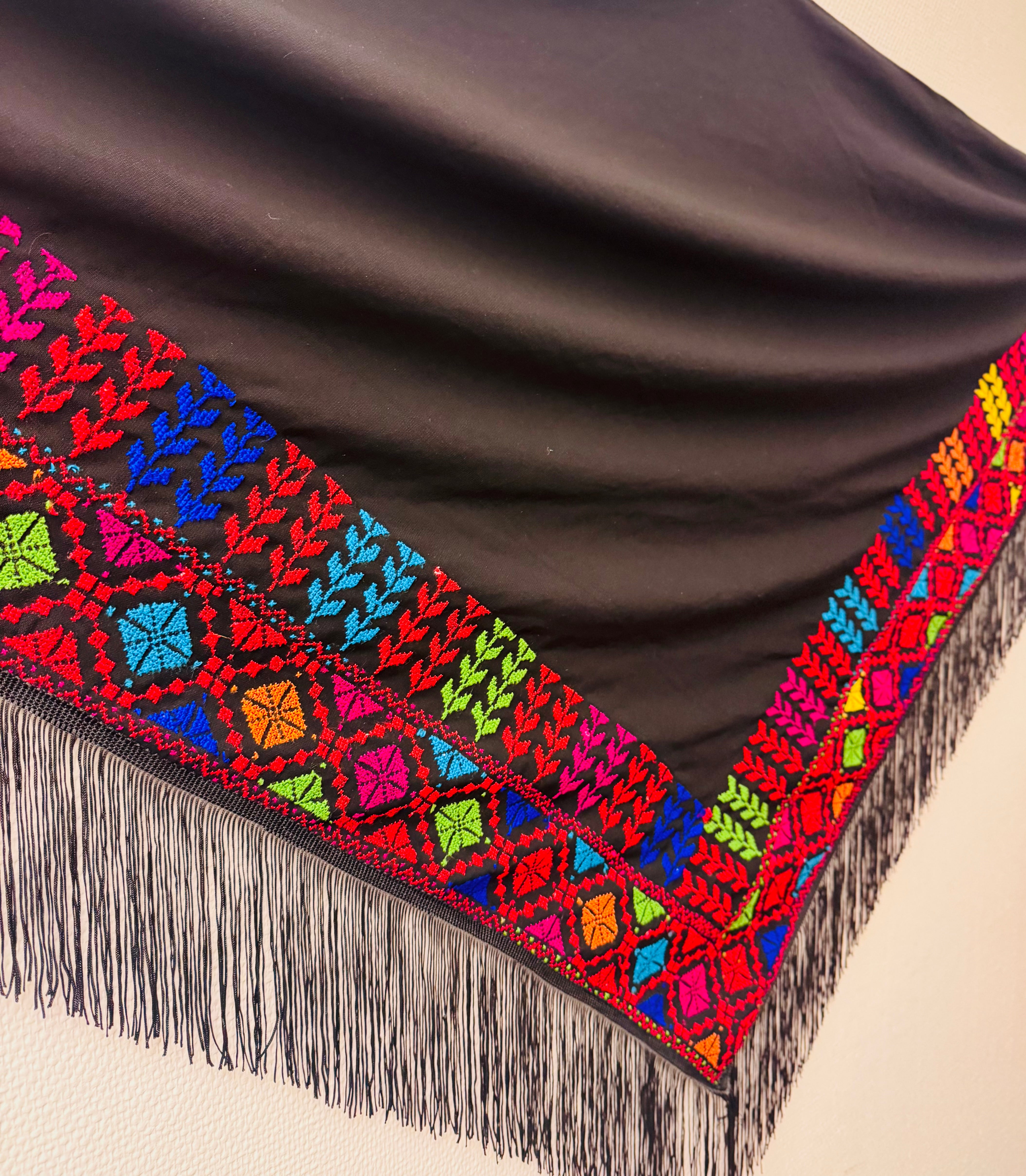 Vinkelbilde av fargerikt palestinsk tatreez-broderi med detaljerte geometriske mønstre, tradisjonelt håndverk fremhevet i tekstilstruktur