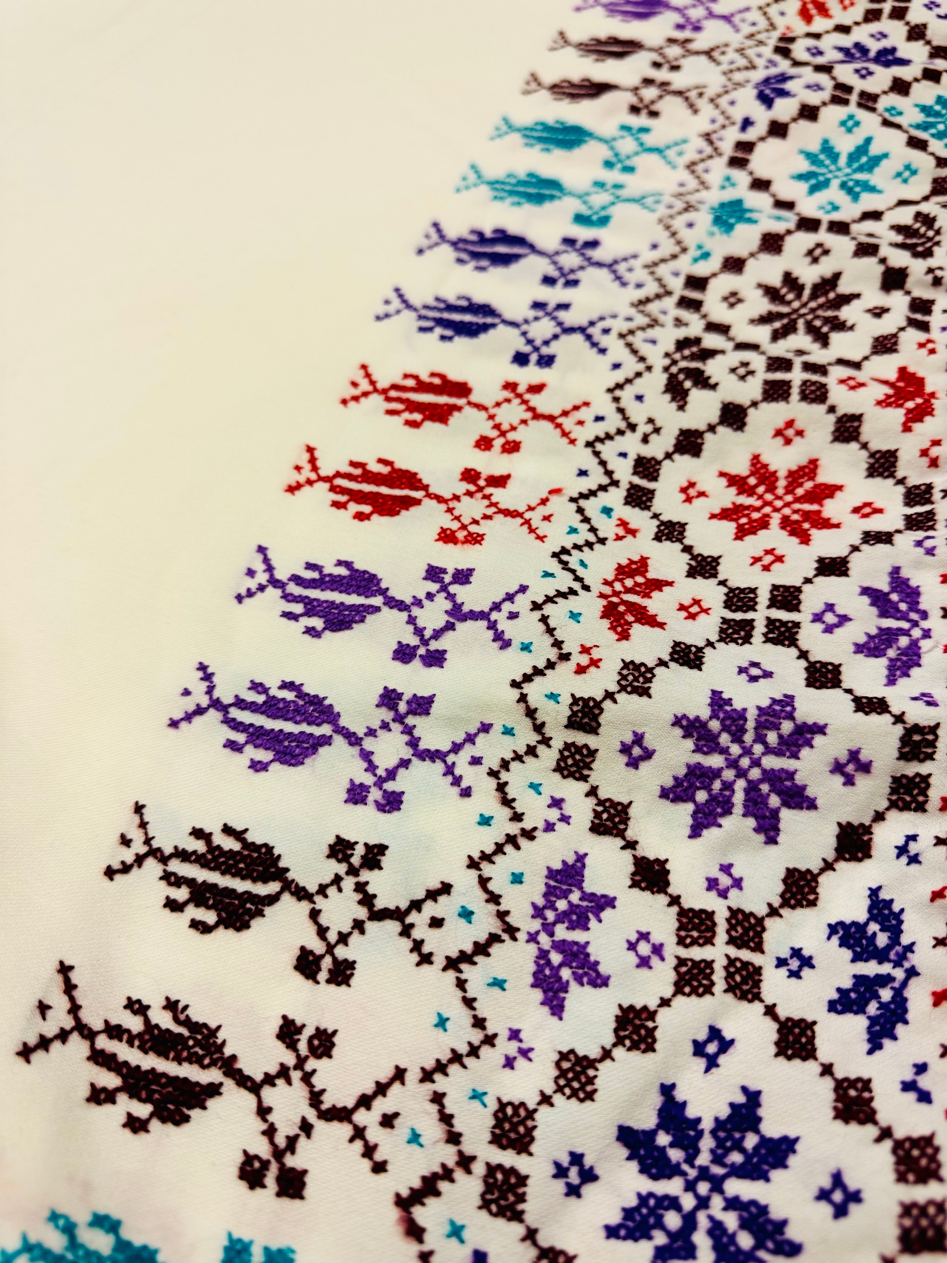Hvitt tatreez-skjerf fotografert fra siden med fokus på broderte palestinske detaljer