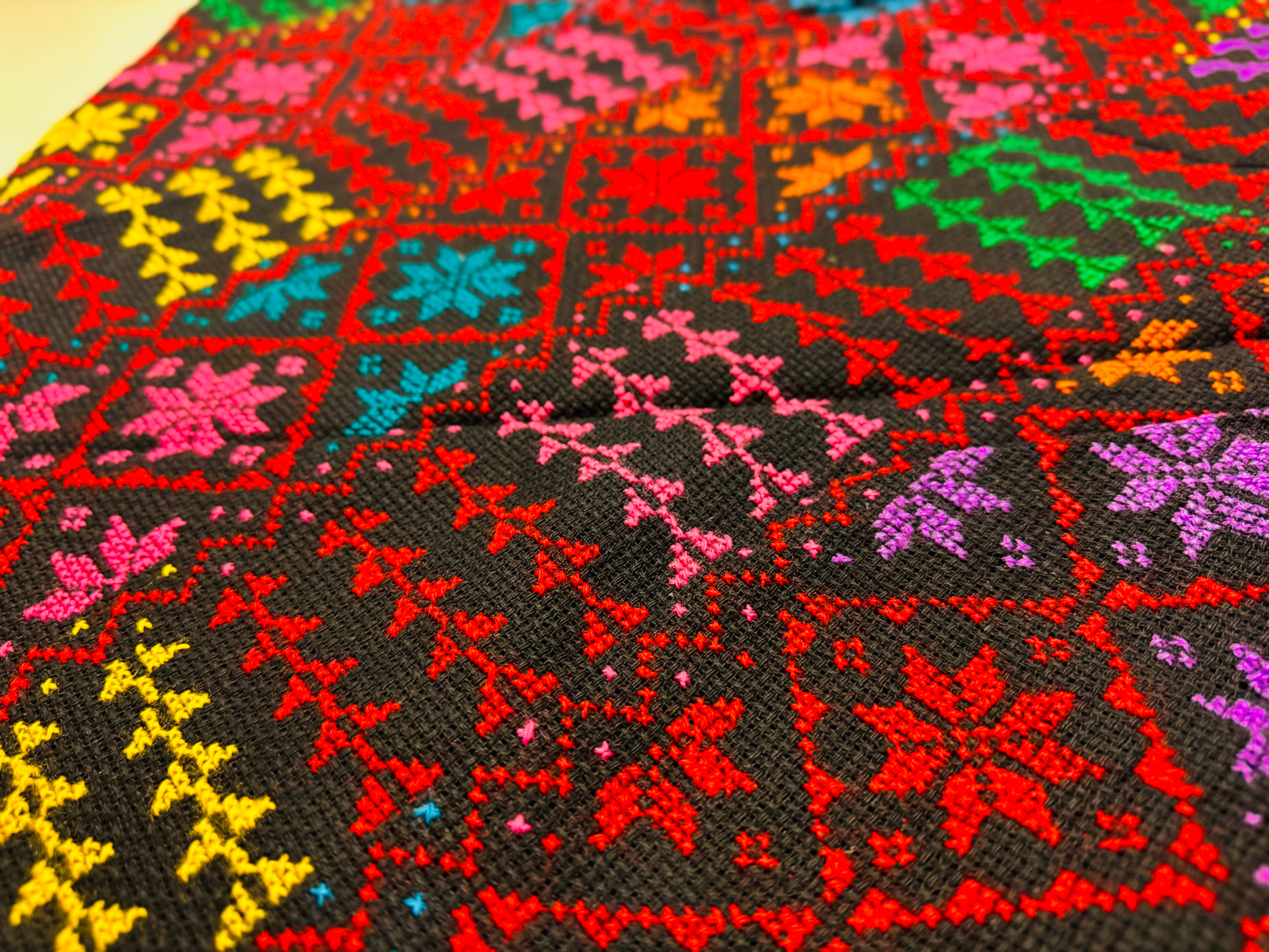Nærbilde av tatreez-sjal med palestinsk broderimønster vist fra skrå vinkel, detaljert tekstil som fremhever tradisjonelt håndverk