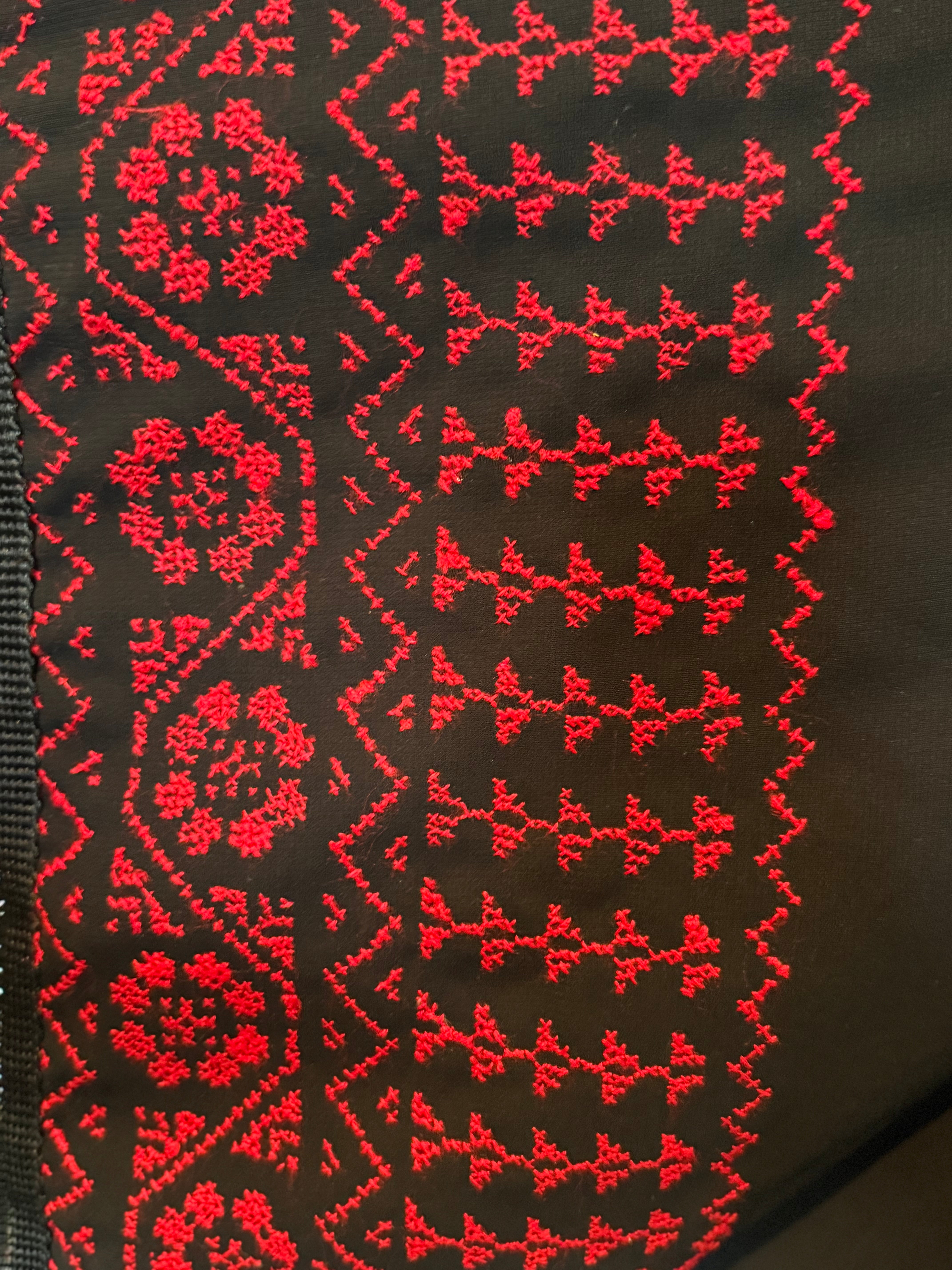 Vertikalt utsnitt av tradisjonelt tatreez-broderi på skjerf, med repeterende symbolske former.