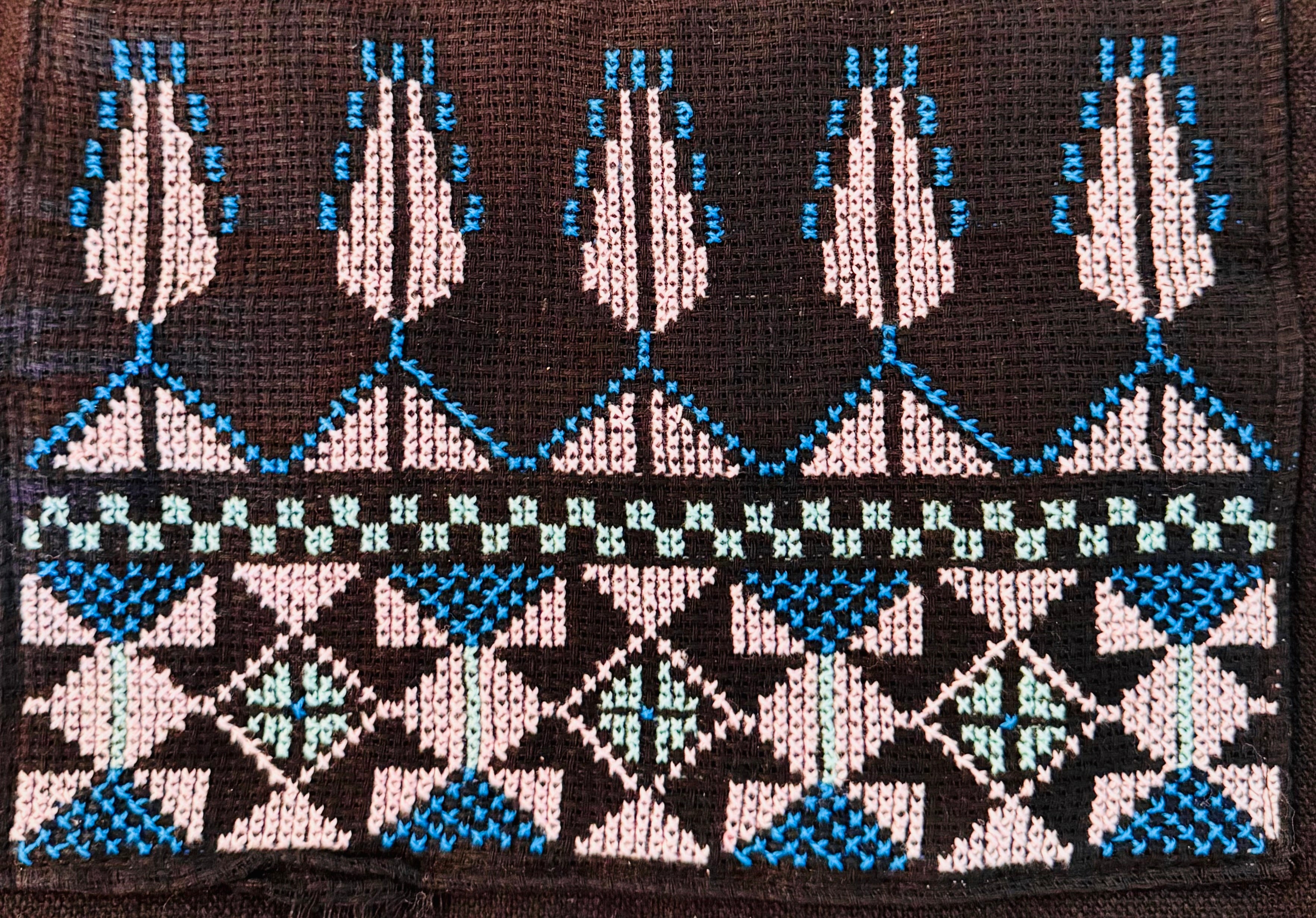 Detaljert utsnitt av palestinsk tatreez på tote bag, der kontrasten mellom tråd og tekstil fremhever håndverket.