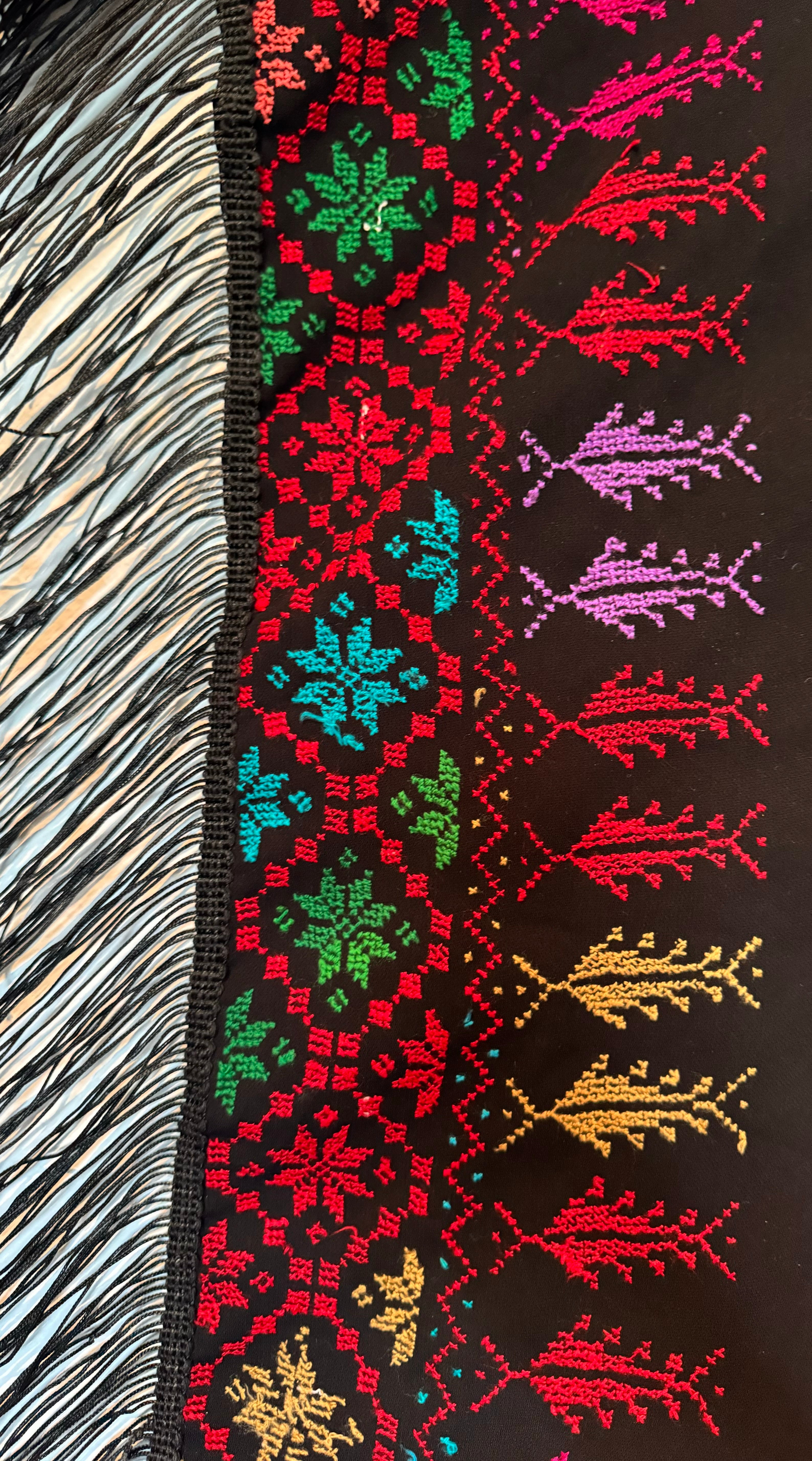 Nærbilde av tatreez-mønster på skjerf, med symmetriske former brodert i sterke farger.