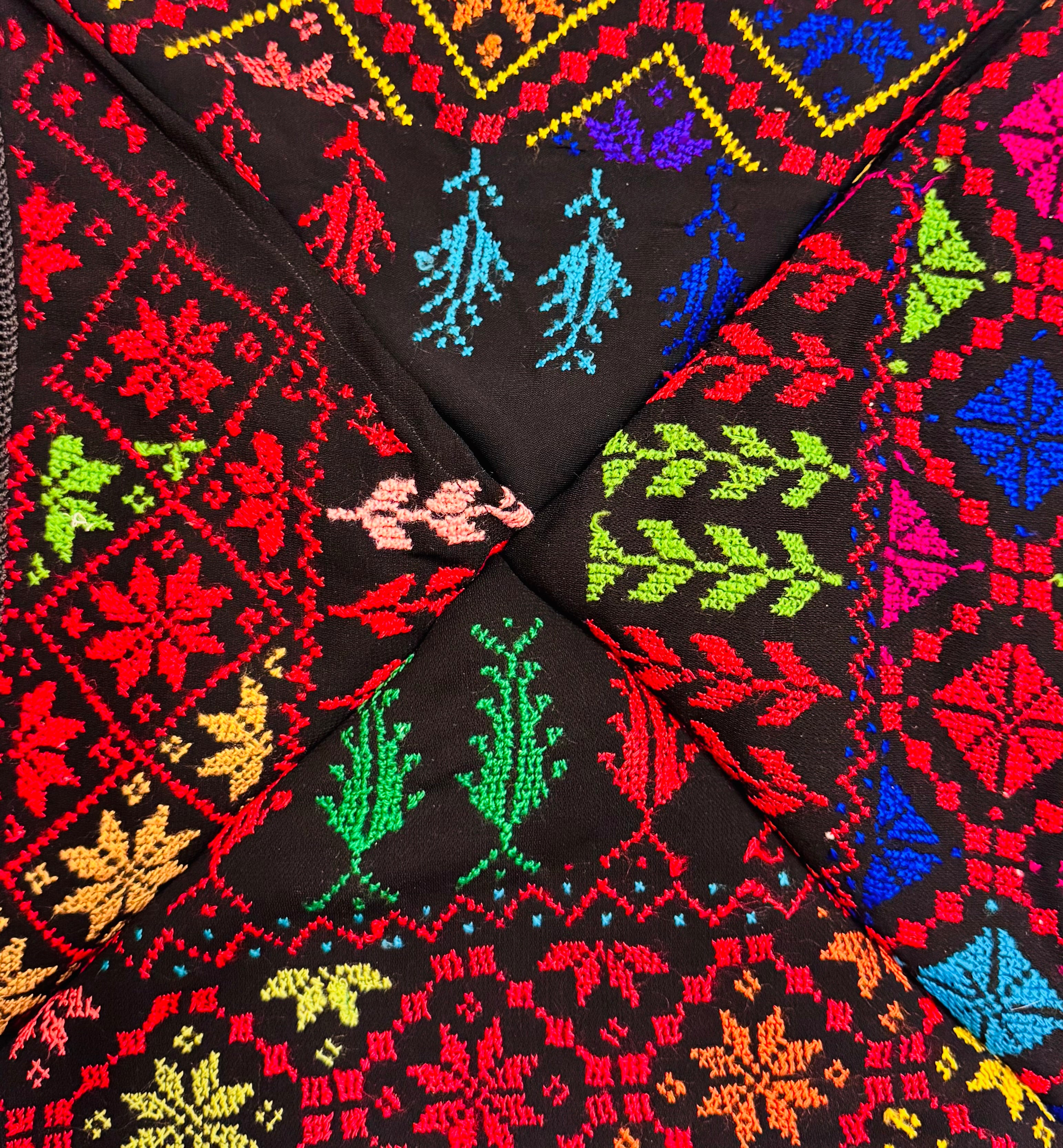 Nærbilde av fargerikt palestinsk tatreez-broderi med detaljerte geometriske mønstre, tradisjonelt håndverk vist i tekstilstruktur