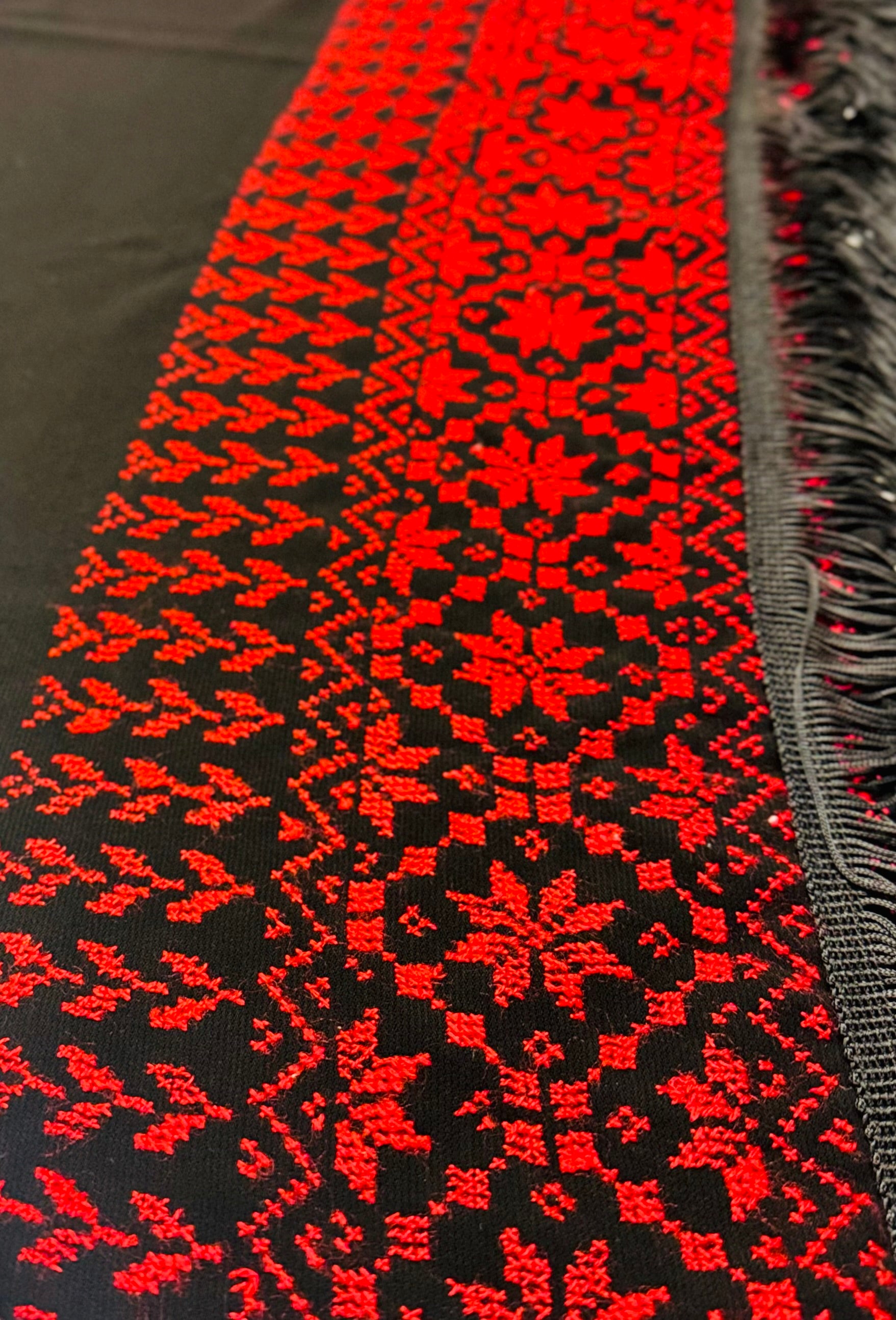 Vinkelbilde av rødt og svart tatreez-sjal  med tydelig palestinsk broderimønster