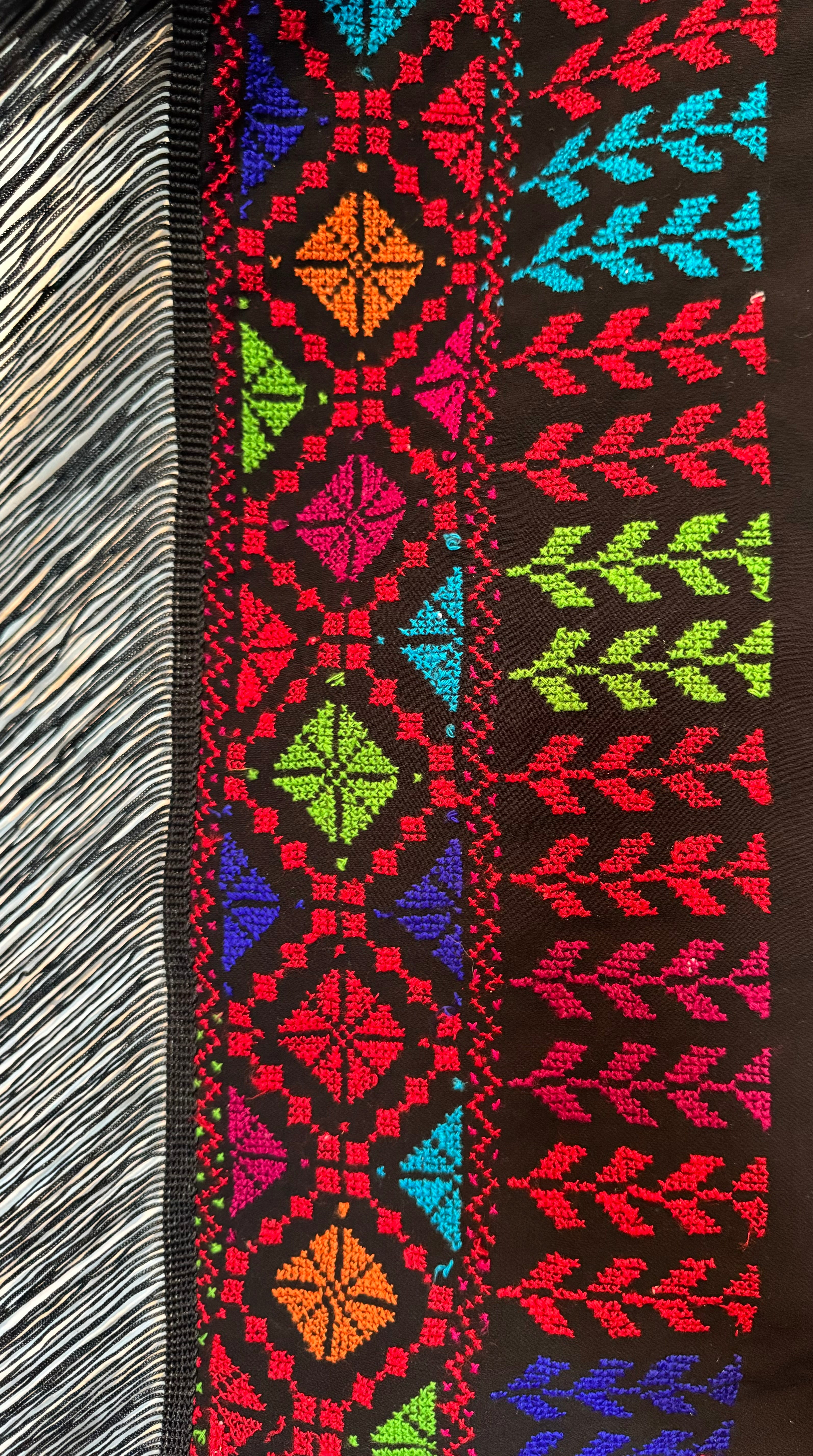 Vertikalt utsnitt av tradisjonelt tatreez-broderi på et sjal, med repeterende bladformer.